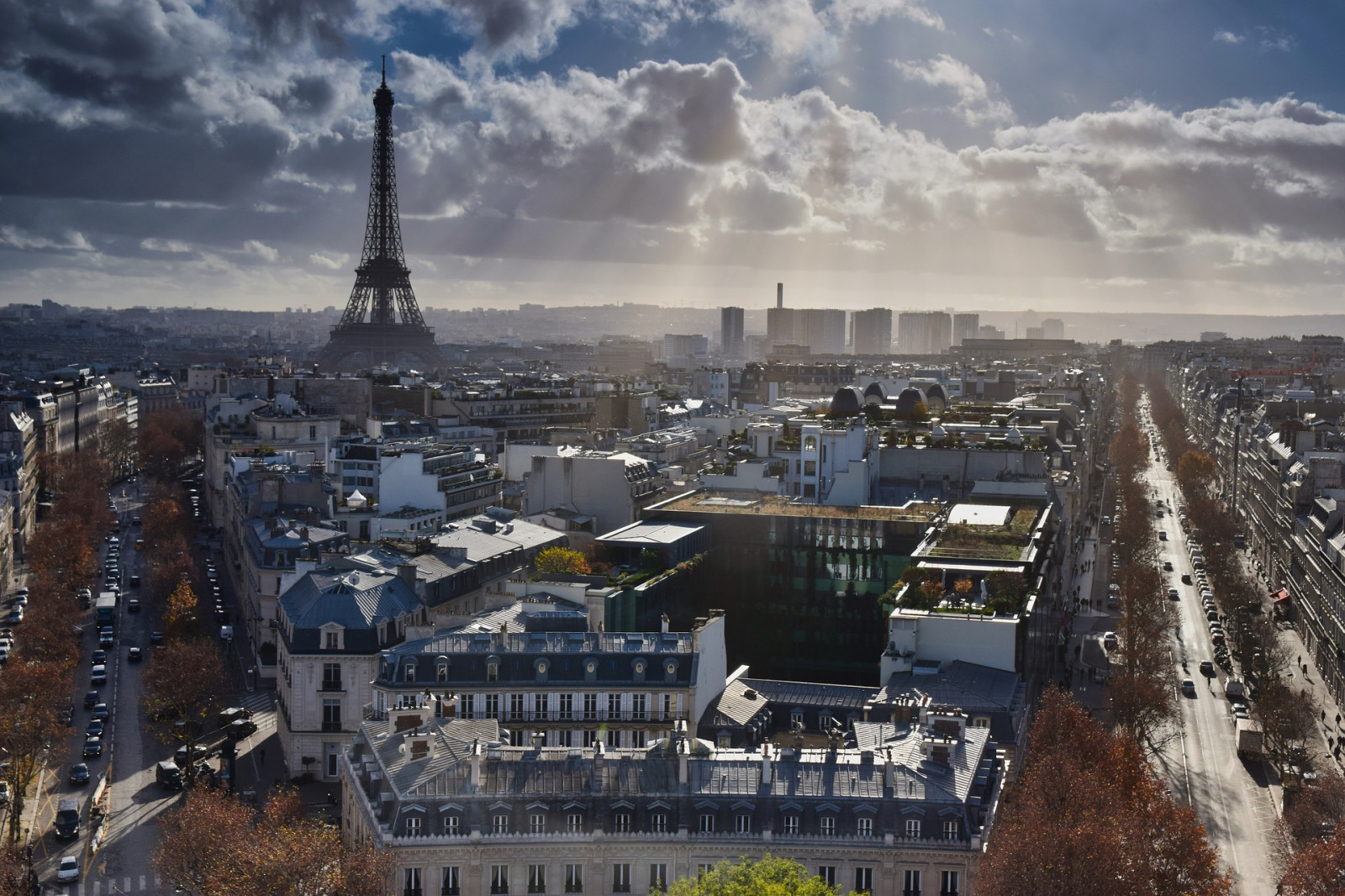 Na zdjęciu znajduje się panorama miasta - Paryża. Po lewej stronie widoczna jest Wieża Eiffla. Na pierwszym planie znajdują się dachy domów i kontury ulic. 