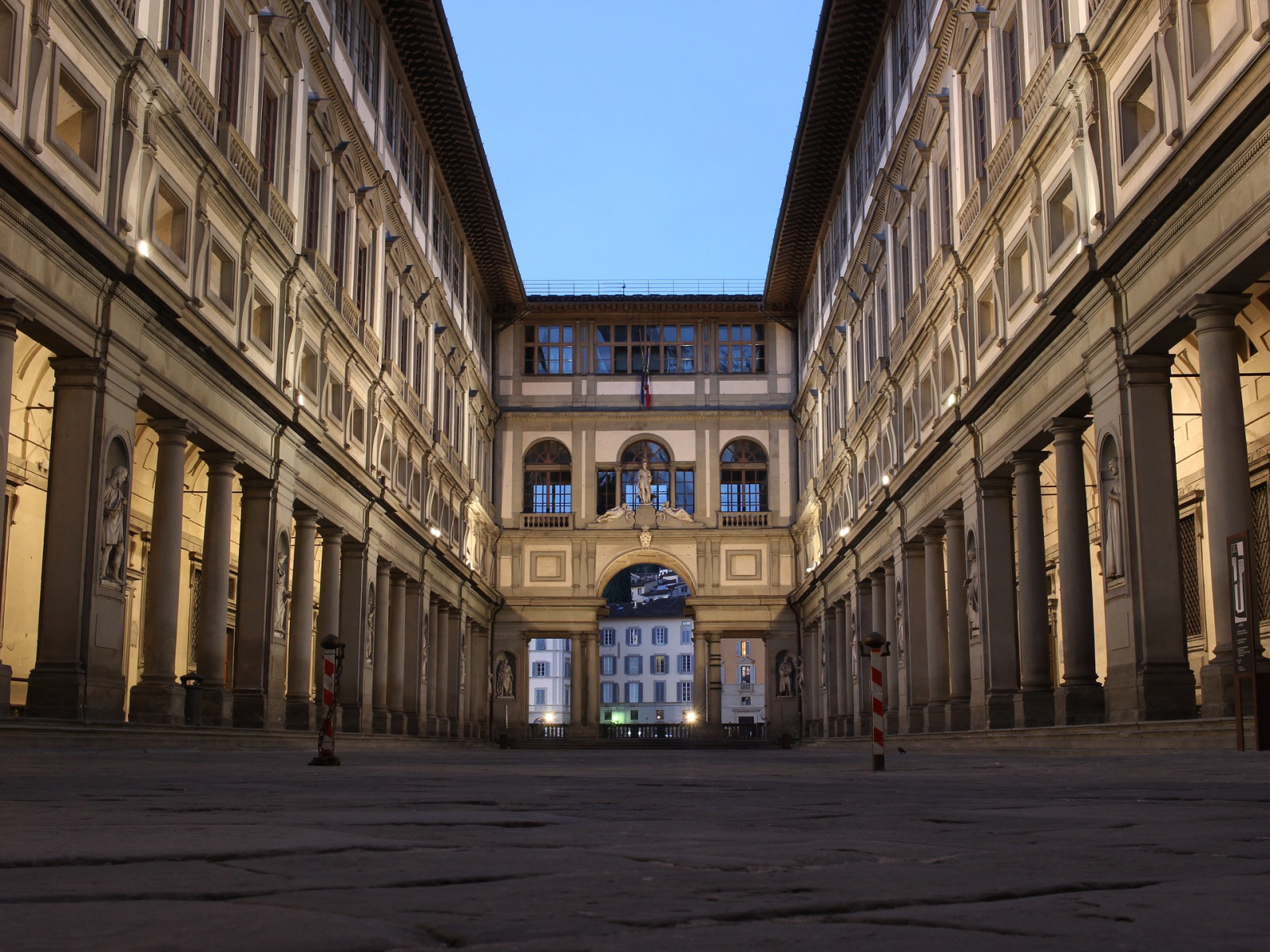 Na zdjęciu znajduje się budynek z kolumnami. jest to Galeria Uffizzi we Florencji. Po lewej i prawej stronie jest szpaler kolumn. W środku znajduje się plac. 