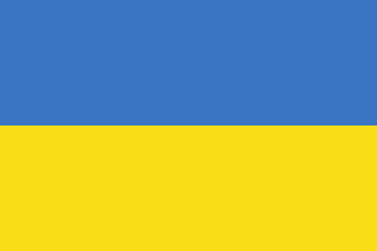 Na zdjęciu znajduje się dwukolorowa flaga Ukrainy, złożona z dwóch poziomych pasów.Na dolnej połowie obrazka jest pasek żółty. Na górnej połowie obrazka jest pasek niebieski. 