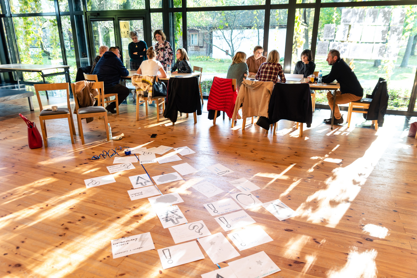 fotorelacja z warsztatów: osoby siedzące przy stole i rozmawiające, trenerzy prowadzący zajęcia, zdjęcie grupowe