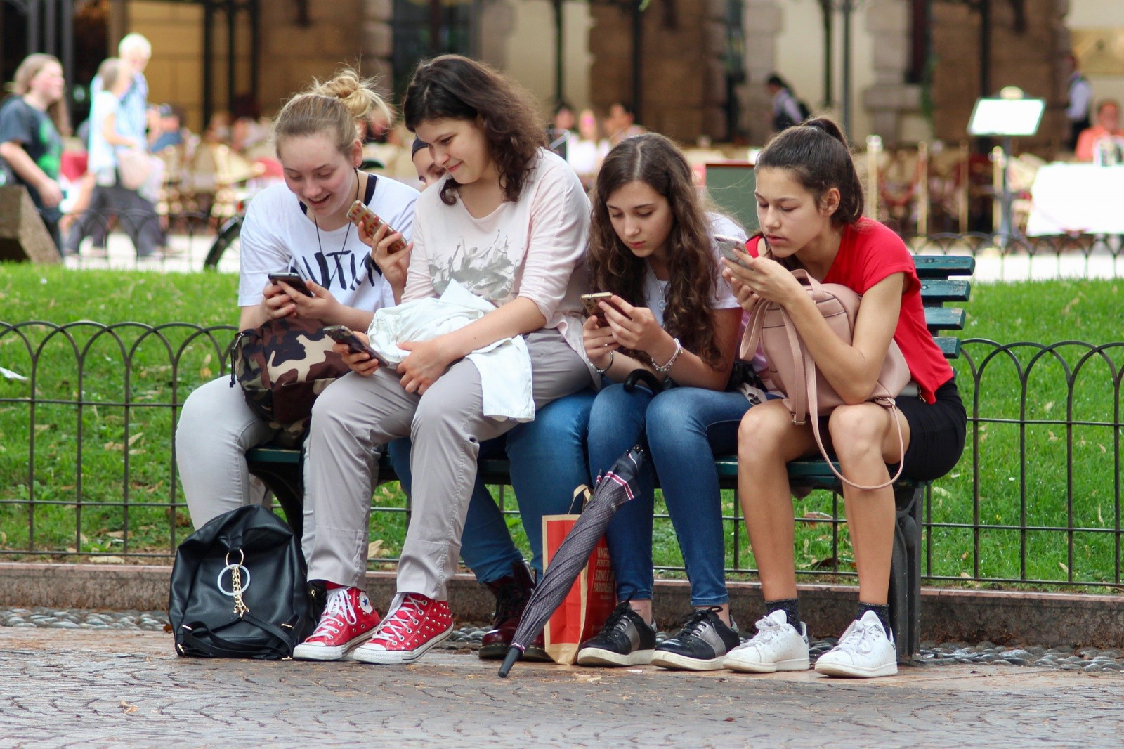 Fotografia przedstawia cztery dziewczynki korzystające z telefonów komórkowych.