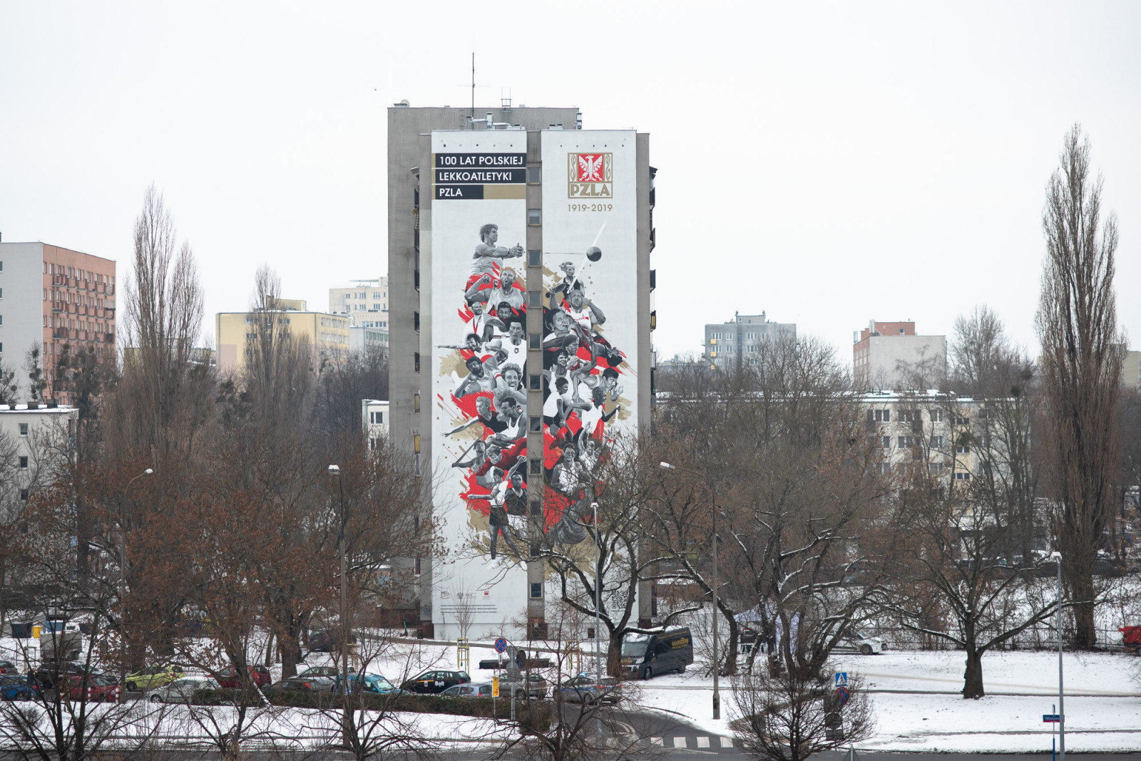 fotorelacja z odsłonięcia muralu, osoby wypowiadające się do mikrofonu, mural przedstawia ilustrację polskich sportowców i napis: 100 lat polskiej lekkoatletyki 1919-2019