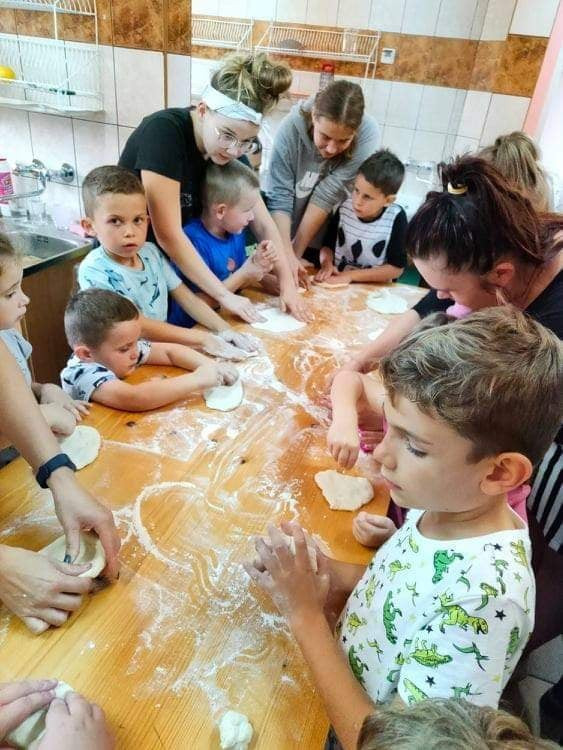Dzieci siedzą podczas warsztatów rozgniatają ciasto.