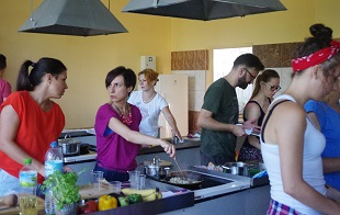 grupa ludzi gotuje w dużej kuchni